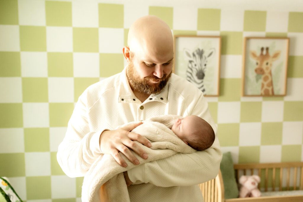 Dad holds newborn in nursery during   newborn session 