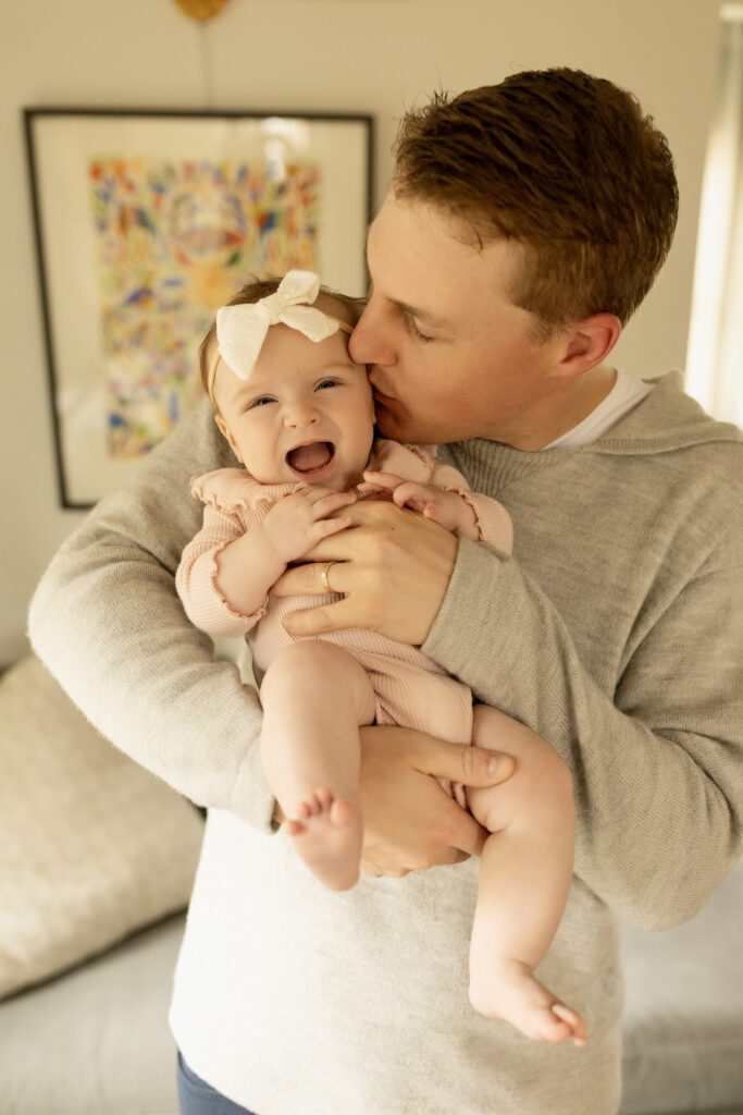 St Paul dad kissing daughter during a newborn photo session 